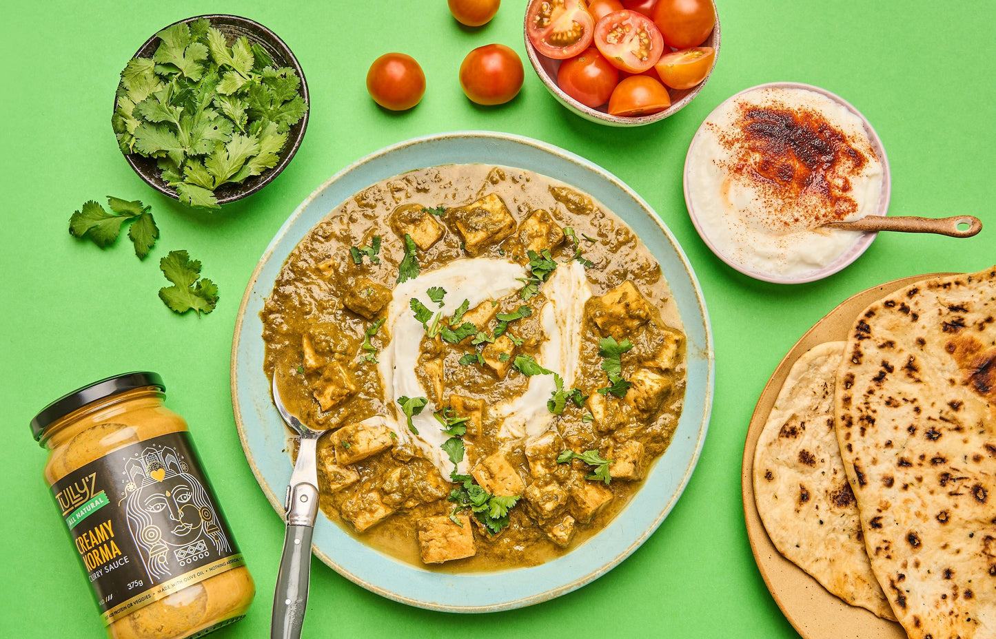 A bowl of Creamy Korma Tofu Curry garnished with fresh coriander, served with naan.