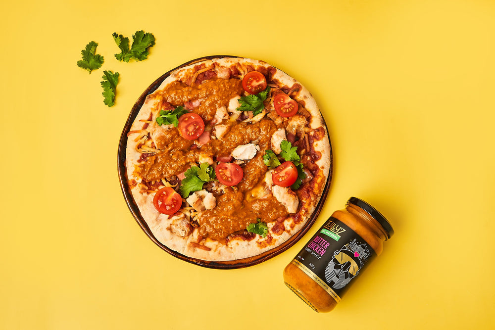A freshly baked Butter Chicken Pizza topped with feta, mozzarella, and a drizzle of spicy mayo.